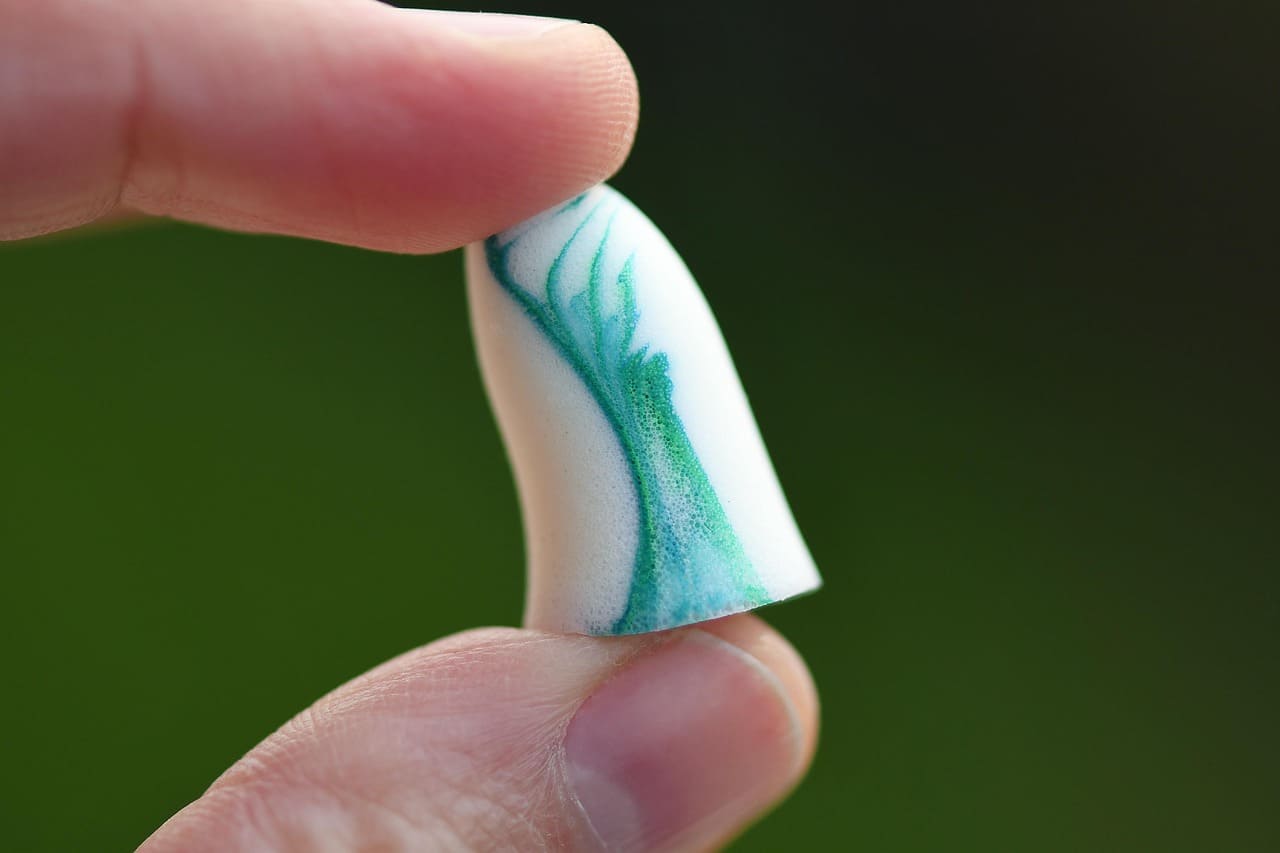 손가락으로 귀마개를 들고 있다