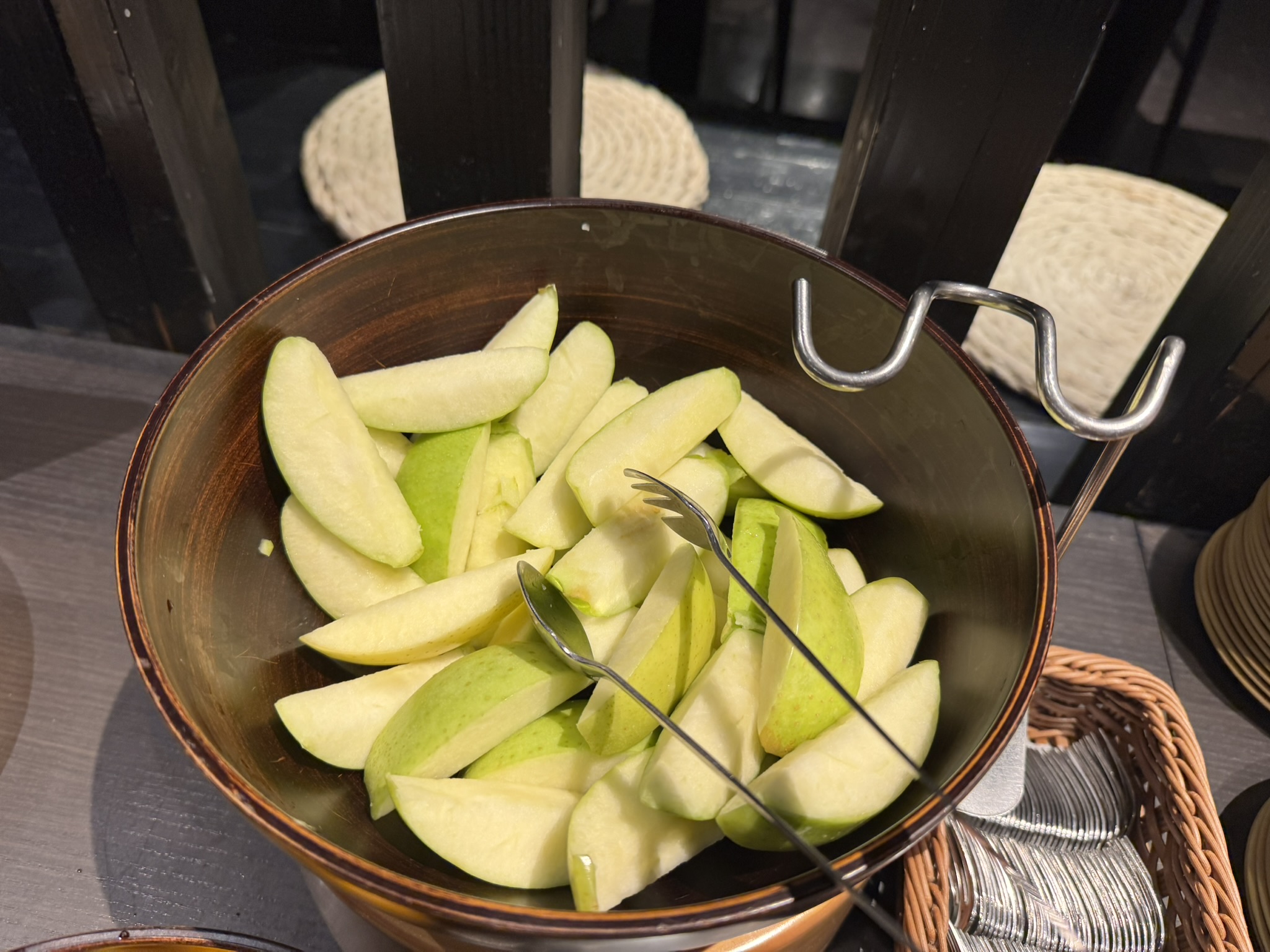 커다란 그릇에 가득 담긴 신선한 아오모리 사과 슬라이스. 껍질째 먹기 좋게 잘린 초록빛 사과들이 집게와 함께 놓여 있는 신선한 모습.