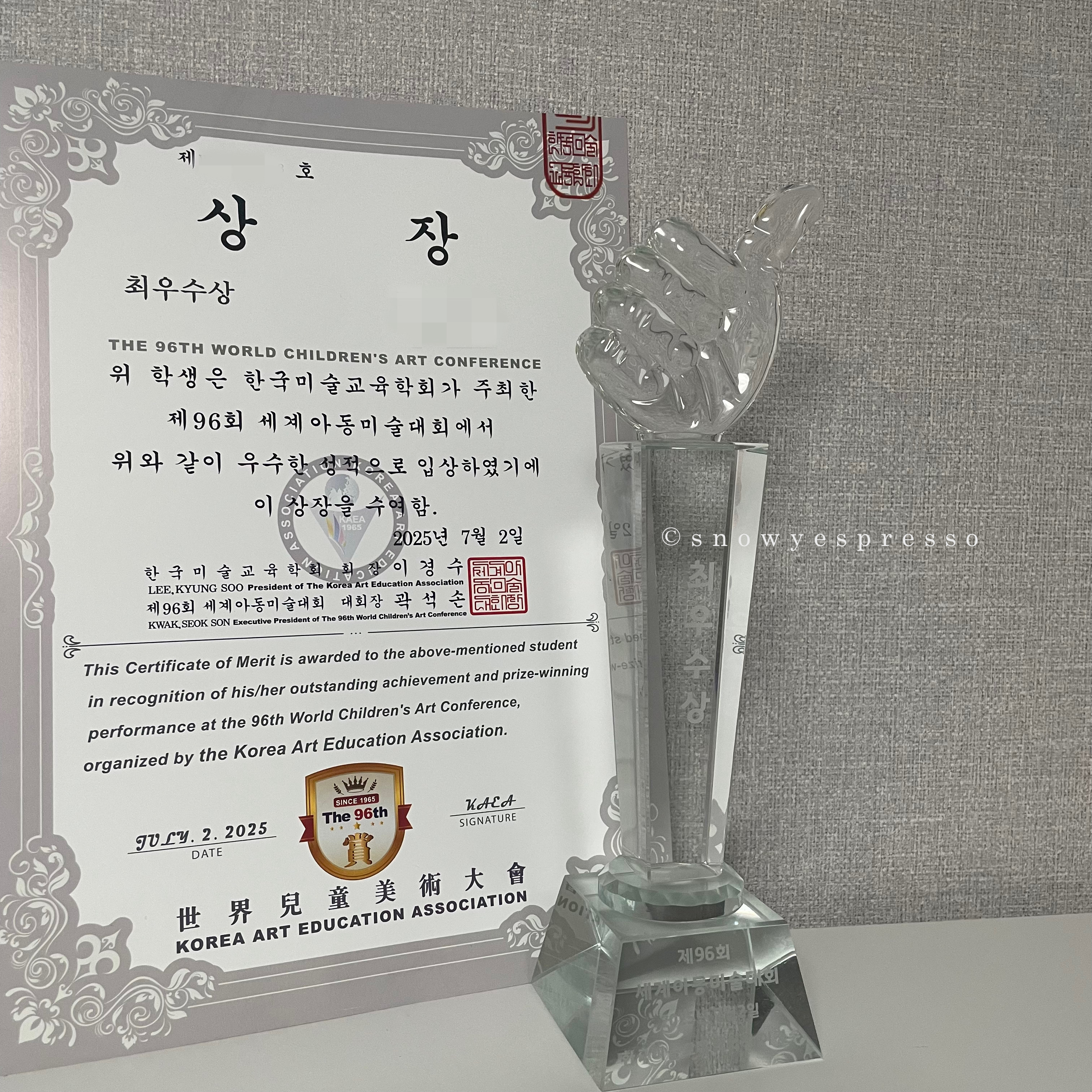 제96회 세계아동미술대회에서 받은 최우수상 상장과 엄지척 모양의 크리스털 트로피