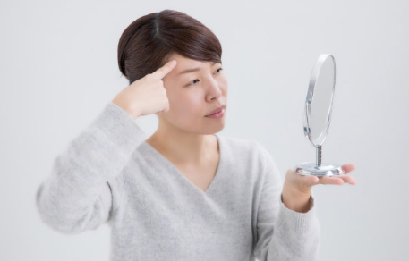 이마의 주름을 신경쓰는 여성.