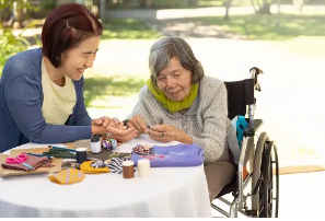 치매환자와 보호자가 테이블에서 만들기를 하고 있는 모습