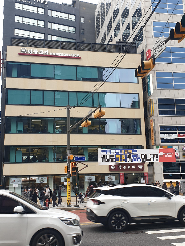횡단보도 건너 5층 빌딩에 명동교자 간판이 있다.