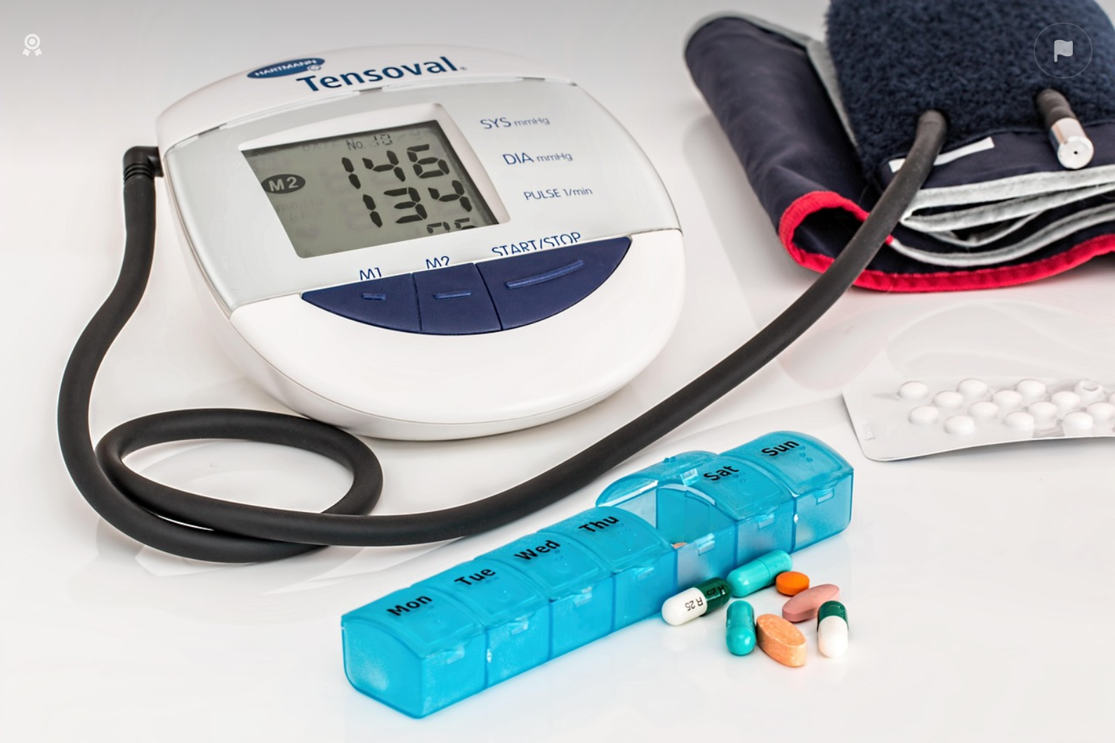 가정용 자동 혈압계와 약 정리함, 다양한 종류의 약물이 함께 놓여있는 모습