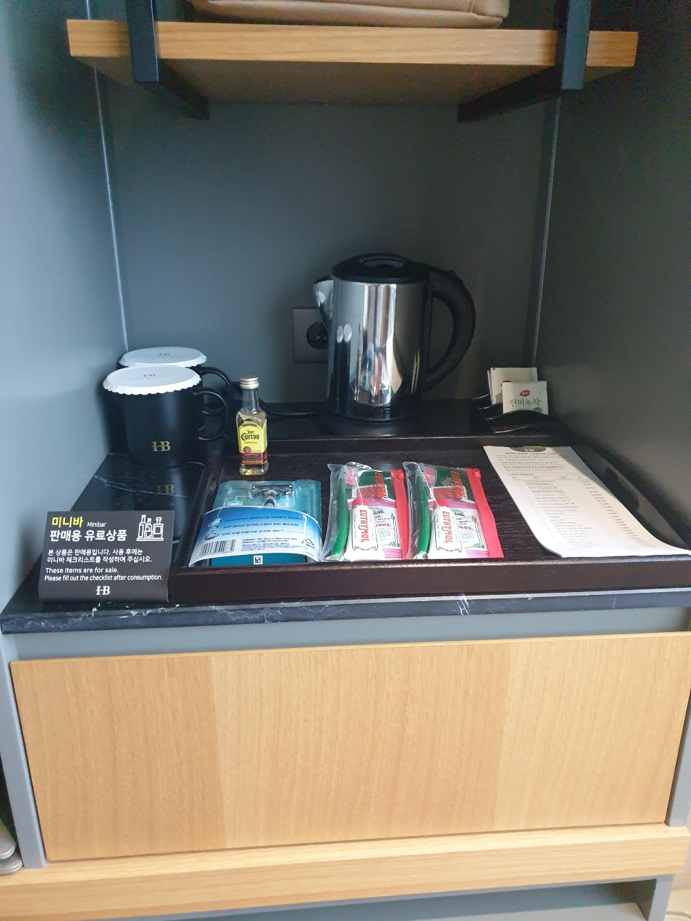 미니바에 일회용 도구와 작은 양주 그리고 포트가 보인다.