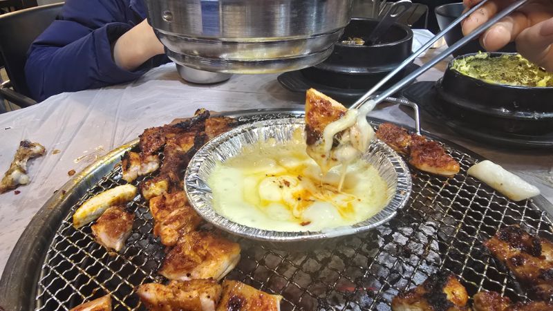 매콤한 양념 닭갈비를 고소한 치즈 퐁듀에 찍어 먹는 모습