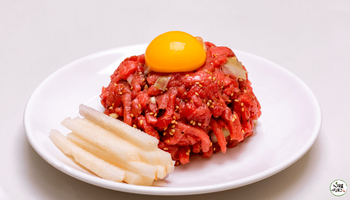 흰접시위에 육회와 배가 올려져있다