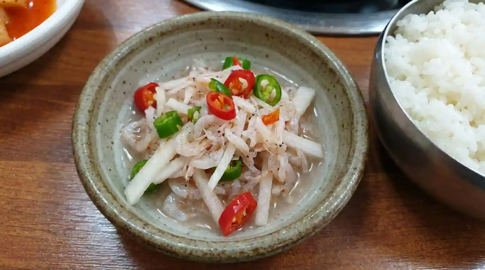 밥반찬으로 작은 접시에 다진 무, 썬 고추, 새우젓이 섞여 있는 모습.