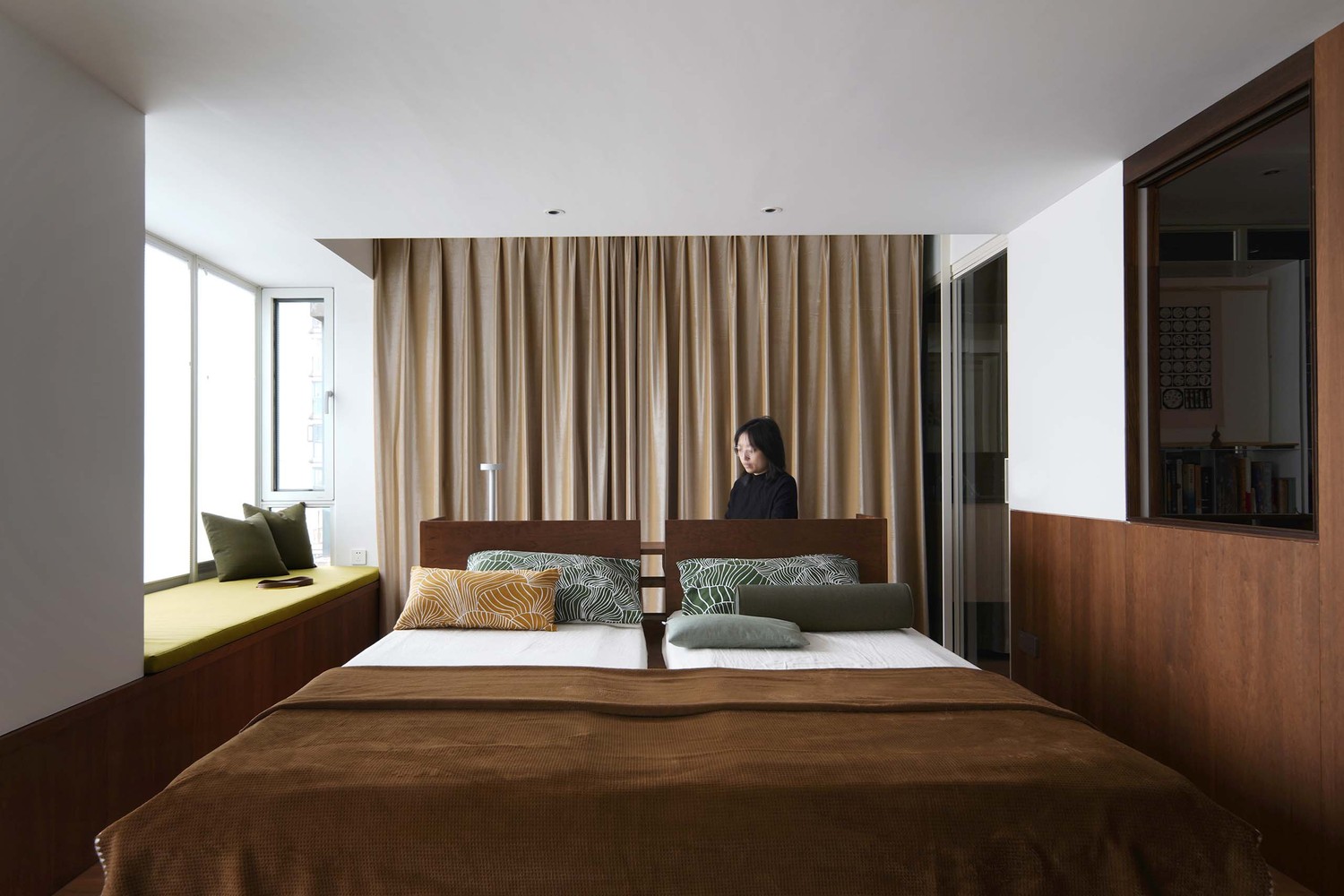 가운데-침대가-있으며-뒤에-한-여성이-서서-바라보고-있다