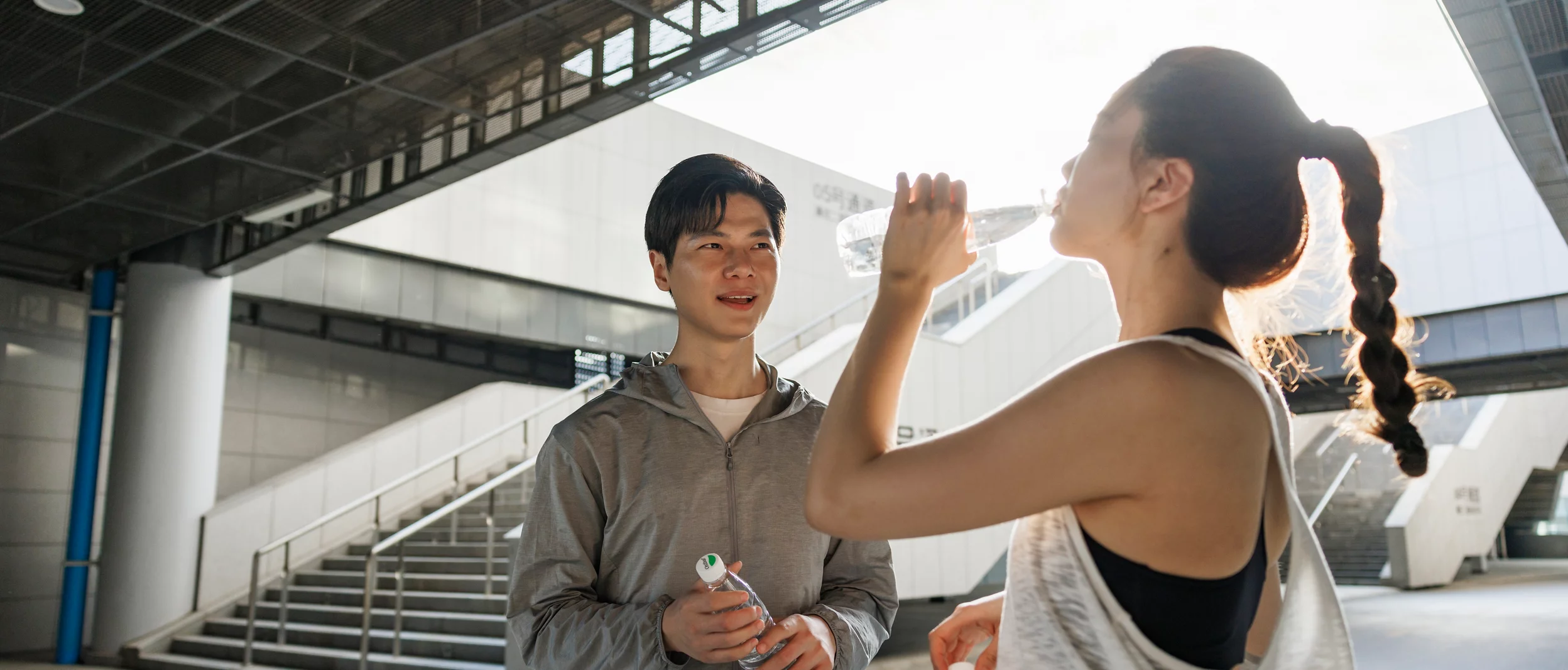 젊은 남녀가 운동을 마친 후 수분을 보충하는 모습의 사진