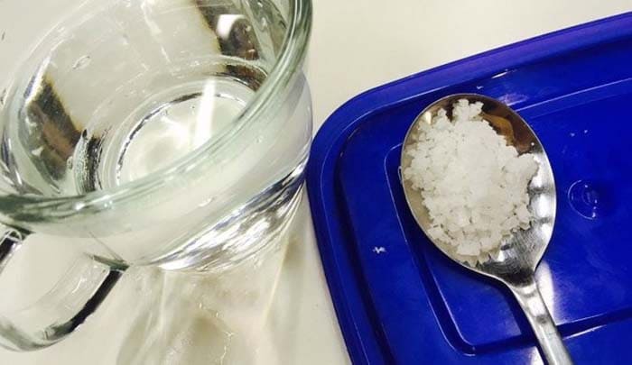 굵은 소금 한 스푼을 물에 넣는 모습