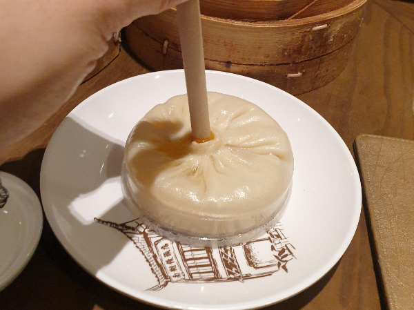 접시 위에 큰 만두가 놓여 있다. 그 만두에는 빨대가 꽂혀있다.