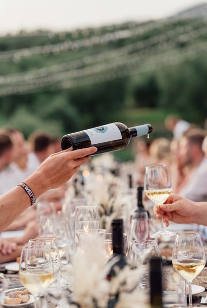 여러 사람들이 식당 테이블에 앉아 서로 와인을 따라주고 있는 사진