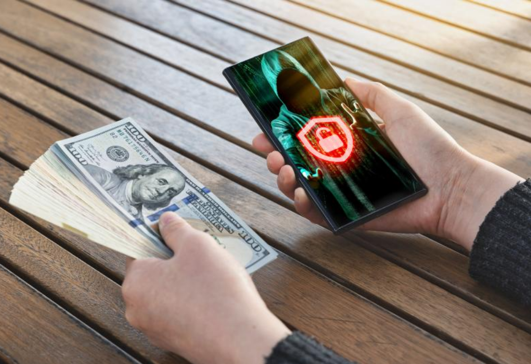 한 남성이 왼손에는 달러 뭉치를 오른손에는 스마트폰을 쥐고 있다.