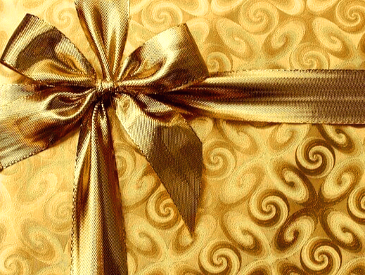 황금색 천 포장지로 싸인 선물 상자가 있고 황금 리본으로 예쁘게 포장됐다.