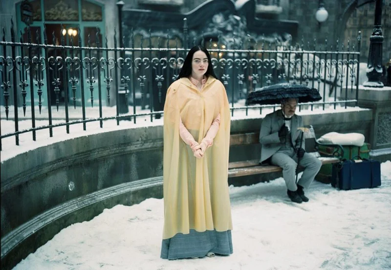 가여운 것들에서 눈 덮힌 거리를 걷는 두 남녀 주인공