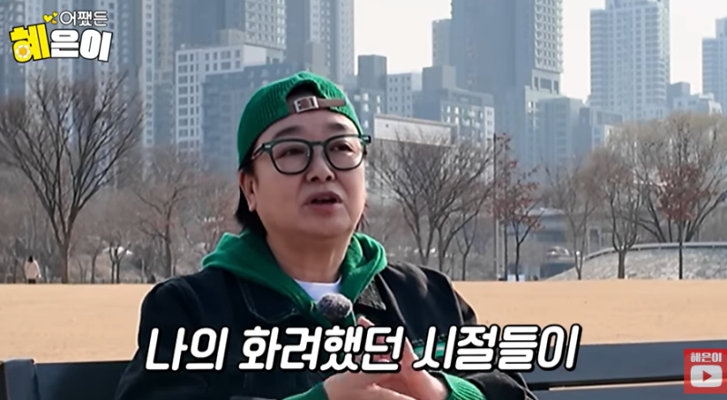 혜은이가 초록색 모자와 안경을 쓰고 야외에서 이야기하는 모습
