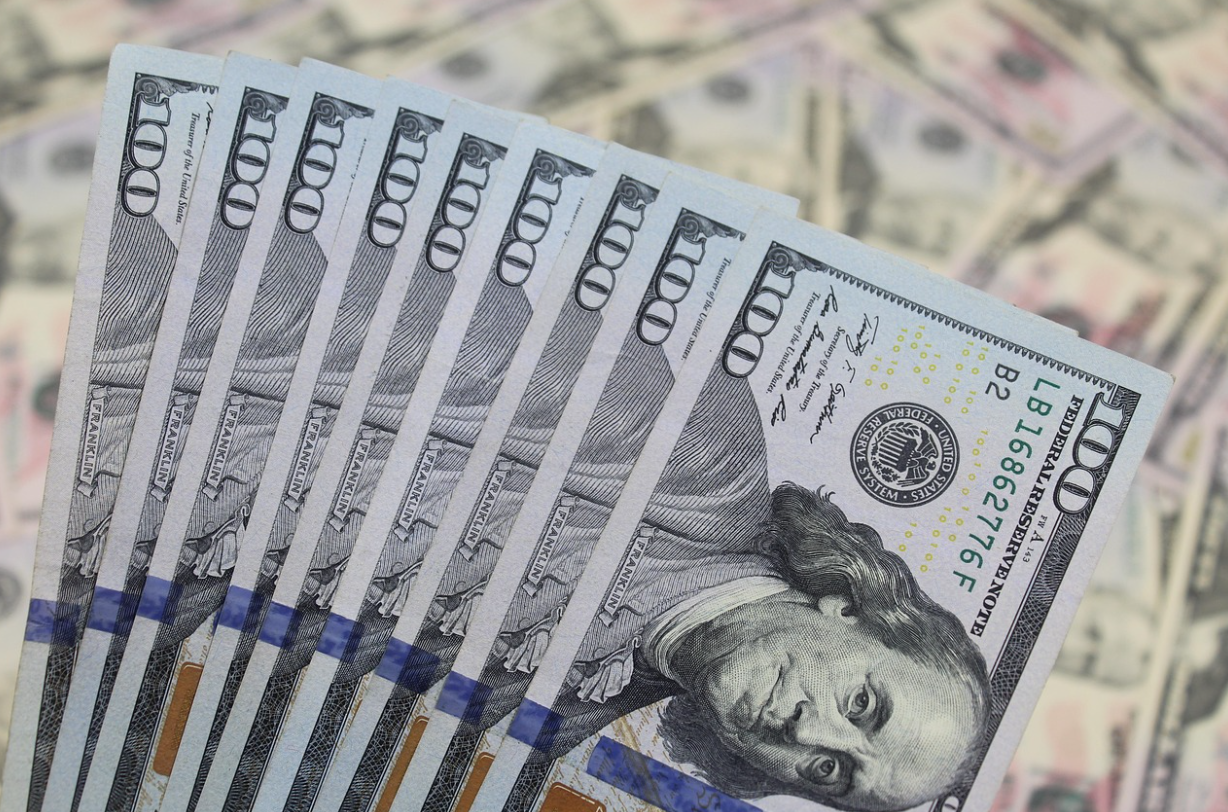 포커스 아웃된 달러를 뒤에 두고 들고 있는 100달러 뭉치