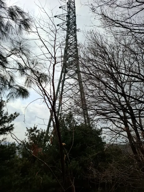 산꼭대기에 에펠탑처럼 웅장하게 서 있는 전기 송전탑 (An electric transmission tower standing grandly like the Eiffel Tower on a mountain peak)