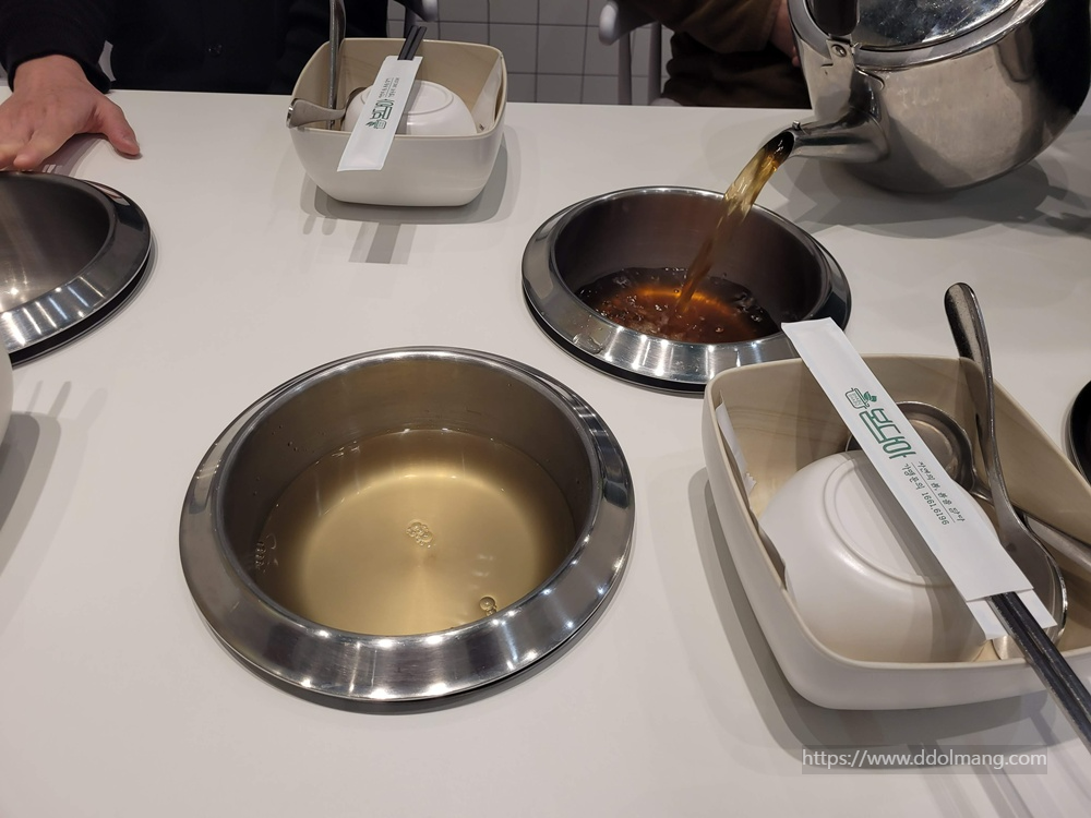 냄비에 주전자의 육수를 붓는 장면