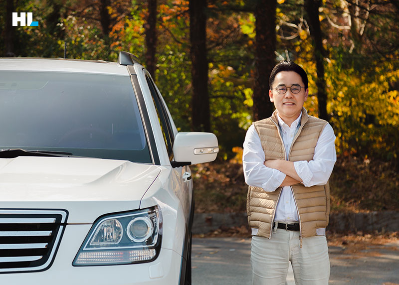 자동차 옆에서 팔짱을 낀 채 서 있는 이현용 팀장