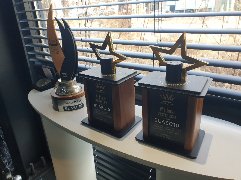 희색 테이블 위에 트로피와 메달이 진열되어 있다. 2023년 2024년은 1등 트로피다.