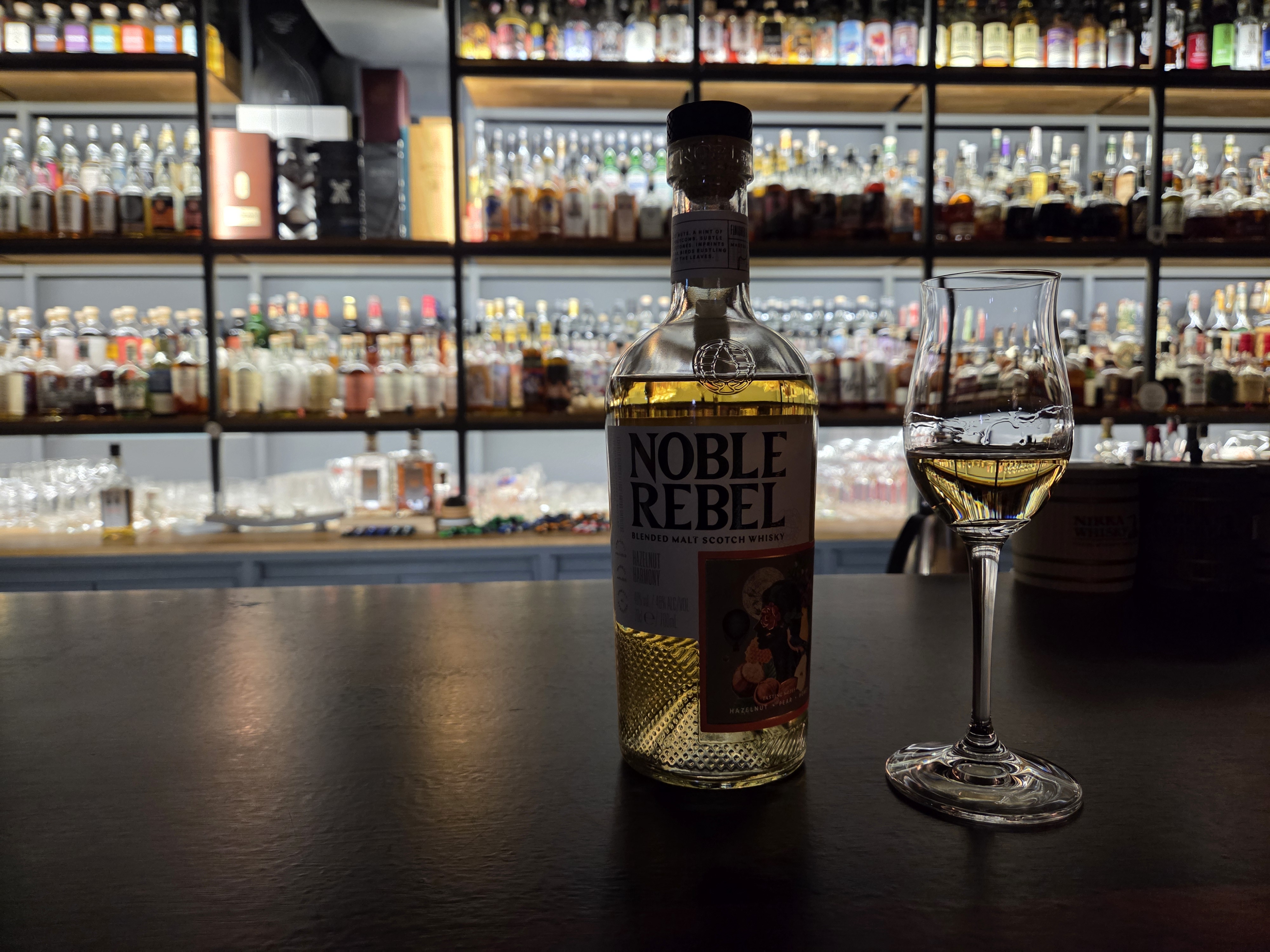 바밤 카운터 위에 놓인 노블 레벨(Noble Rebel) 위스키 잔과 병
