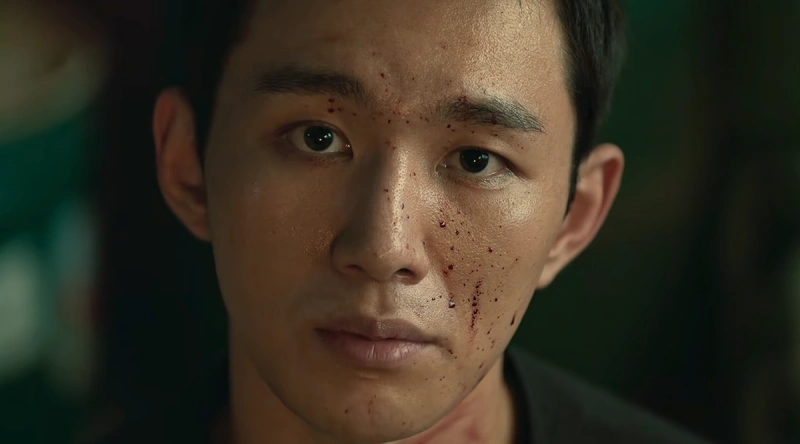 얼굴에 핏방울이 묻어 있는 독전 2의 락 캐릭터