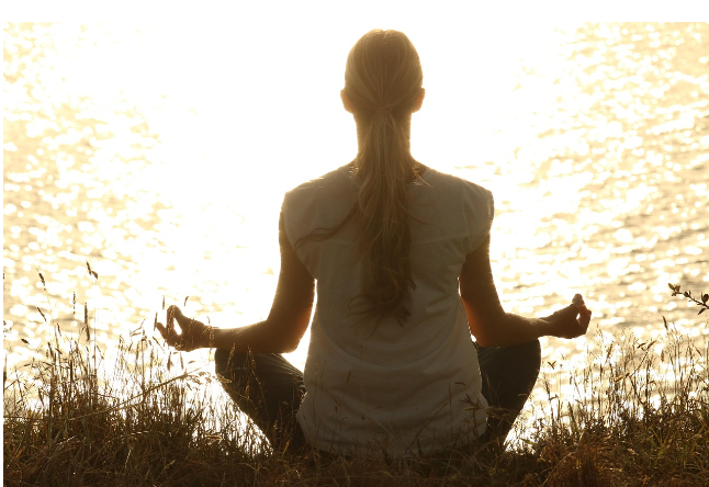 노을빛 물가에서 명상 자세로 앉아 호흡을 가다듬는 사람, 스트레스 완화와 마음의 안정감을 표현한 장면