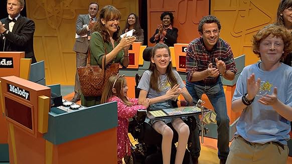 Out of My Mind 퀴즈쇼 장면&amp;#44; 멜로디가 가족과 친구들과 함께 박수를 받으며 기뻐하는 장면