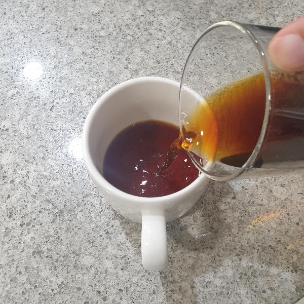 바닥에 머그잔이 있고 서버로 그 머그잔에 추출된 커피를 따르는 모습