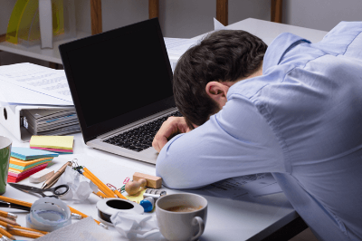 일에 지쳐 피로한 남성이 노트북 앞에 고개를 숙이고 엎드려있다