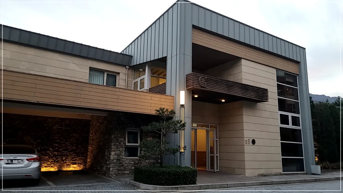 소노펠리체 델피노 빌리지 외관모습. 고급스러운 회색과 나무로 인테리어 되어 있으며 기둥아래 간접조명 2개 왼쪽으로 아반떼가 주차되어 있음