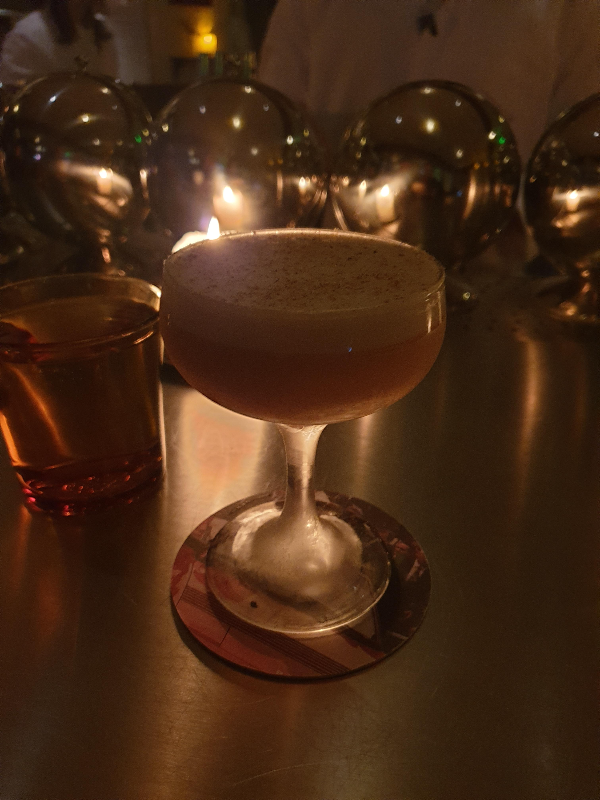 계란 흰자 거품이 보이는 OLIVE &amp; SOUL 칵테일이 테이블 위에 놓여있다.