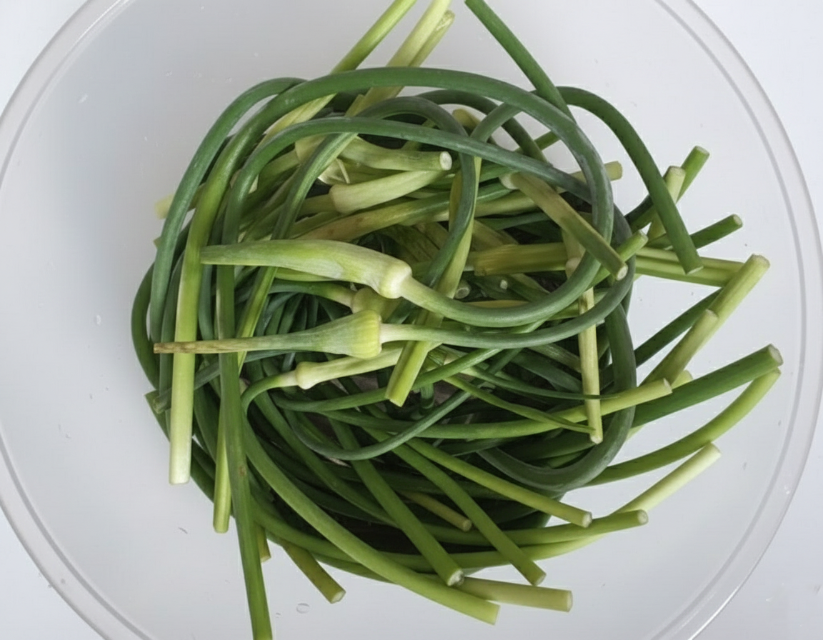 그릇에 담겨 손질을 기다리는 싱싱한 녹색 마늘종들.