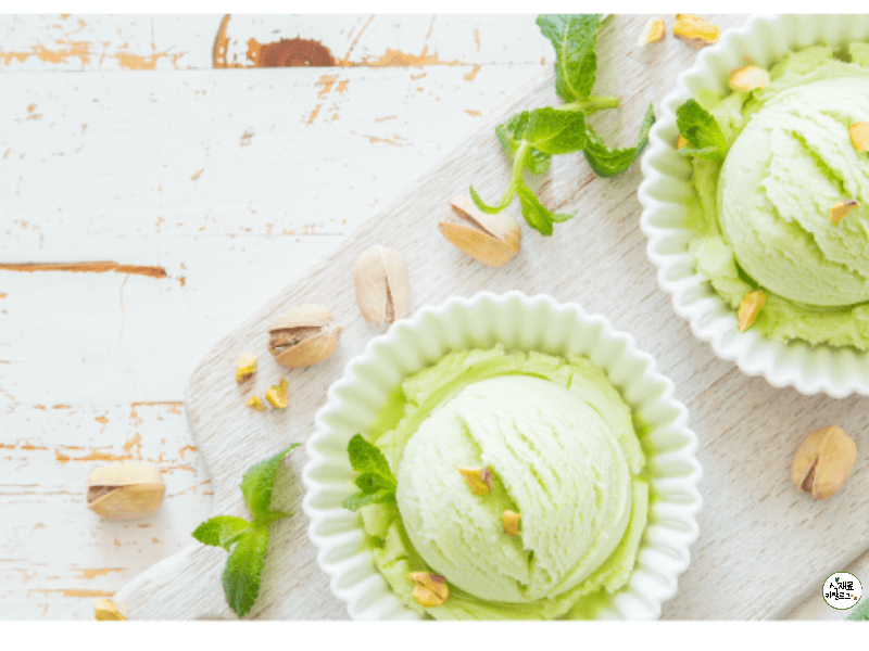 흰사기그릇안에-연두색피스타치오아이스크림이-담겨져있고-흰도마-위에-피스타치오-알맹이와-함께-올려져있다