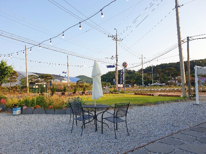 카페서온-야외테라스-전구와-파라솔이-딸린-테이블세트가-보인다