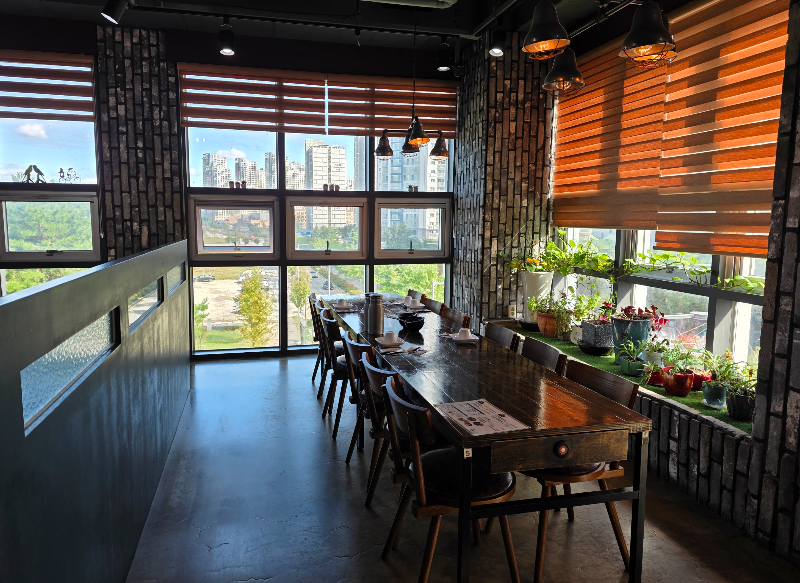 식당 내부 모습. 창가에 테이블과 의자가 보인다.