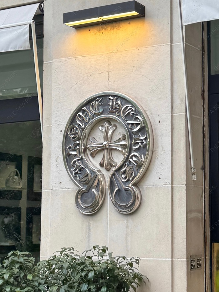 The iconic Chrome Hearts sterling silver horseshoe logo medallion on a classic Parisian stone wall