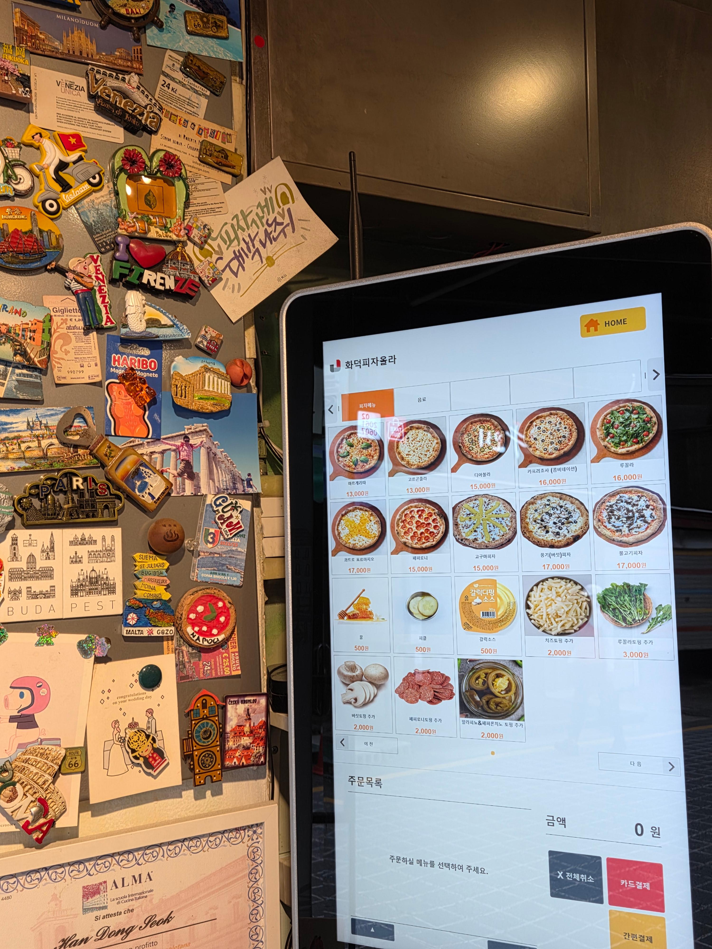 매장 내 키오스크 화면에 표시된 다양한 피자 메뉴와 토핑 추가 옵션