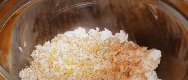 고슬한 흰밥에 들기름 2큰술을 넣은 후 통깨를 넣고 있습니다