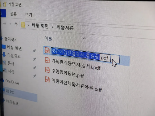 컴퓨터 윈도우 탐색기의 제출서류 폴더 안에서 영유아검진결과서_홍길동.pdf 파일 이름을 수정하기 위해 마우스 커서로 클릭하여 푸른색으로 블록 지정해 둔 모니터 화면 사진