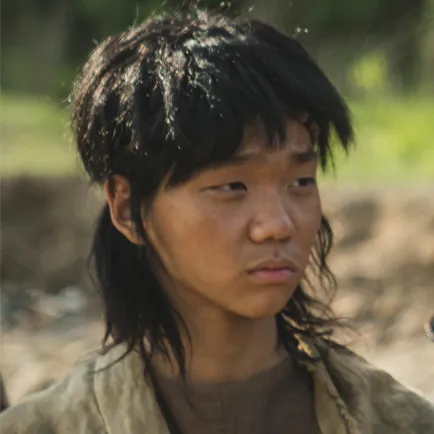 사람이 있는 실외를 배경으로 10대 소년이 허름한 옷을 입고 서 있는 아라문의 검 해때문 캐릭터