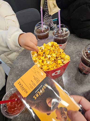 영화 티켓 한 장과 카라멜 팝콘, 콜라를 들고 있는 모습.