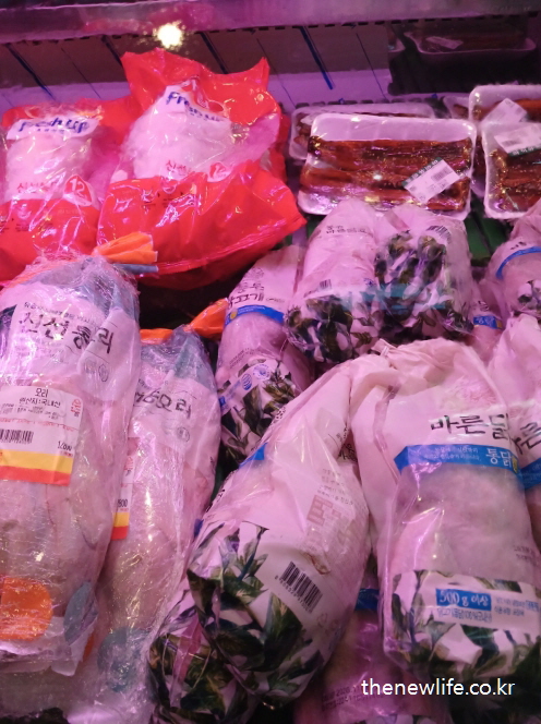 비닐 포장된 통닭과 냉동 닭고기 제품들이 냉장고 안에 진열된 모습