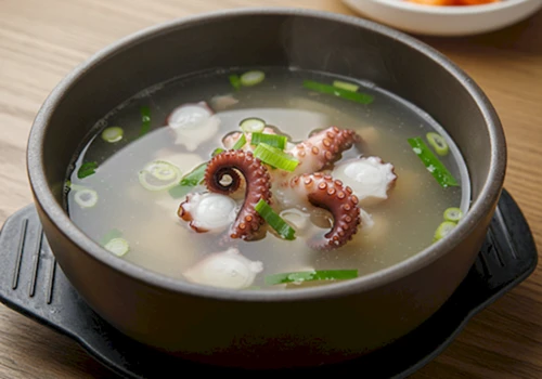 맑은 국물에 낙지와 채소가 들어있는 연포탕 한 그릇을 촬영한 사실적인 사진
