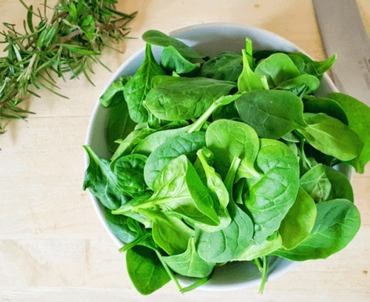 하얀 그릇에 녹색 시금치가 풍성하게 있다.