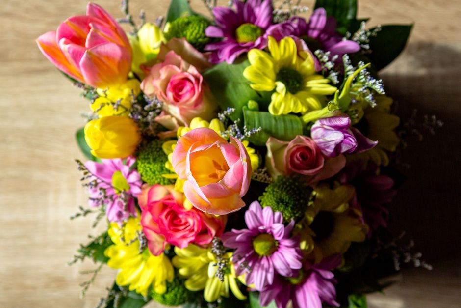 A colorful top view of a floral bouquet with tulips, roses, and daisies.