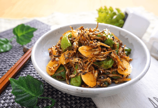 하얀 접시에 멸치볶음이 가득하다. 멸치와 초록색 과리고추가 들어갔다.