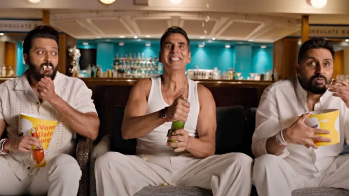 Housefull 5에서 세 남자가 소파에 앉아 팝콘을 먹으며 흥분된 표정으로 화면을 바라보는 장면