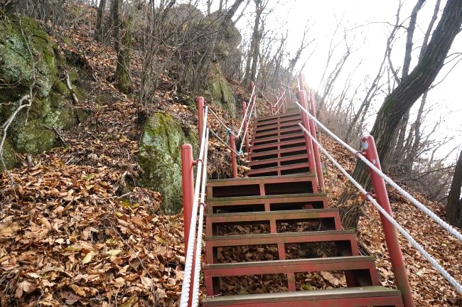두 장의 사진은 모두, 급급경사 철계단, 검붉은 페인팅, 난간 양 쪽에 두 줄 로프난간, 가운데 우뚝한 암봉,